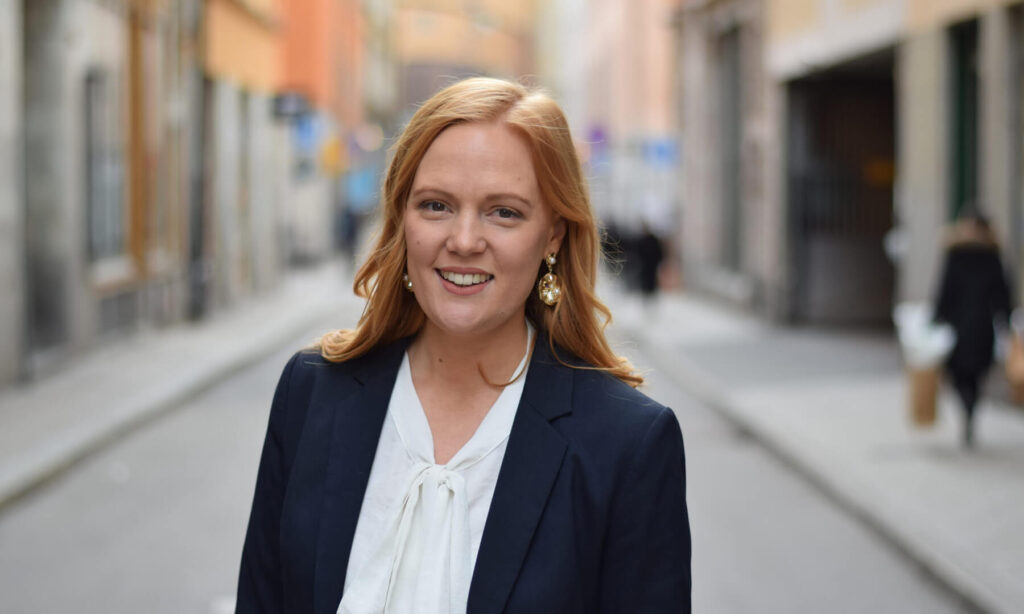 Ung kvinna i kostym, hon ser glad ut